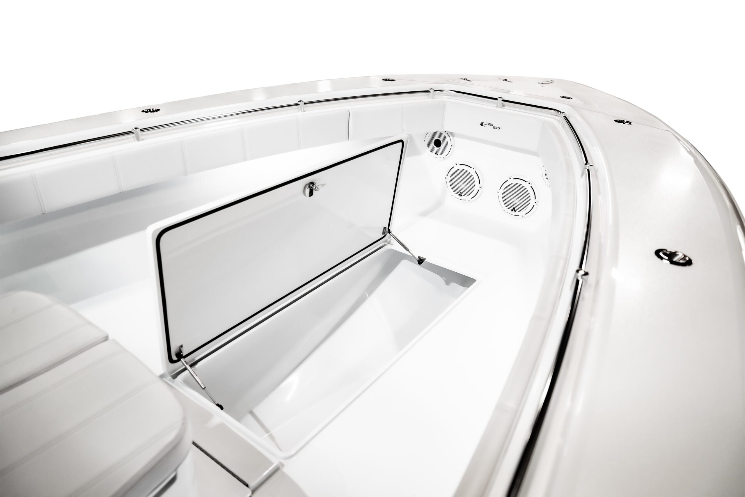 The image shows the interior of a boat, focusing on an open storage compartment and two round ventilation grills. The compartment door is raised, revealing an empty, clean storage area. The image shows the interior of a boat, focusing on an open storage compartment and two round ventilation grills. The compartment door is raised, revealing an empty, clean storage area.
